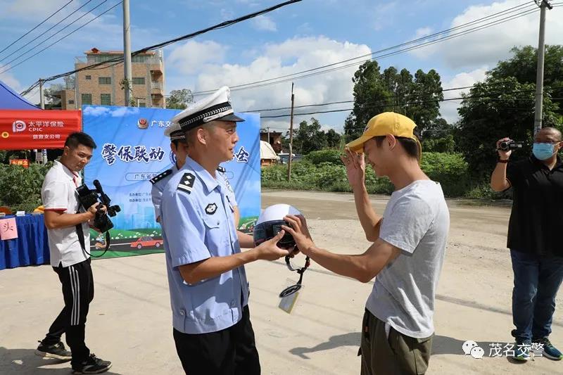 交警给摩托车骑乘人员送头盔，教育和纠正其不佩戴安全头盔的违法行为.jpg